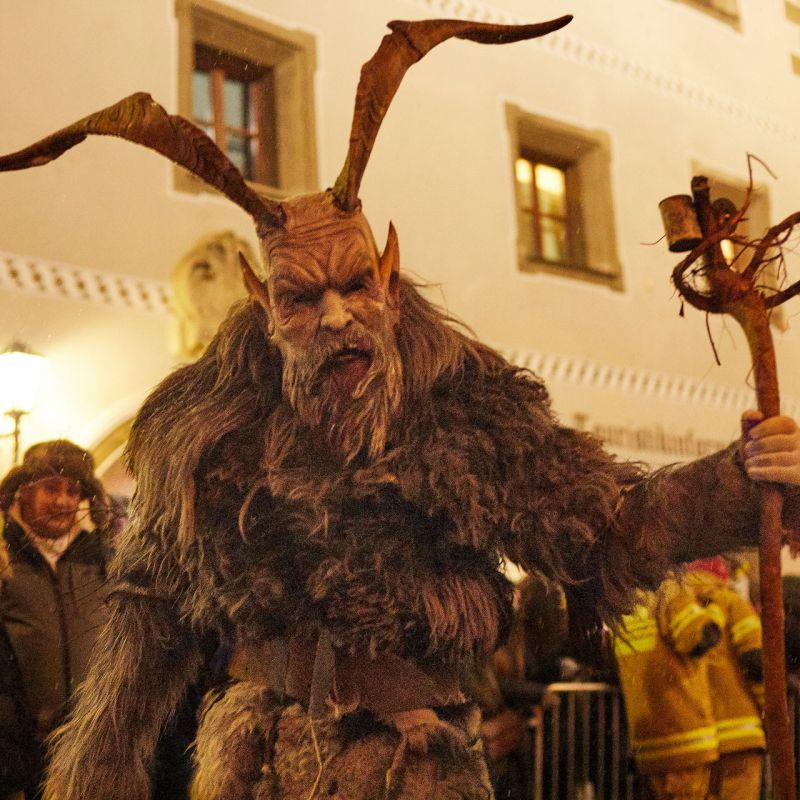 Ein als Krampus verkleideter Mensch mit Fellkostüm und Hörnern bei Nacht vor einem historischen Gebäude im Salzburger Lungau.