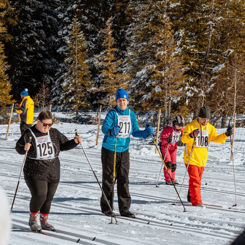 Vier Personen beim Skilanglauf im Schnee, umgeben von verschneiten Bäumen im Salzburger Lungau.