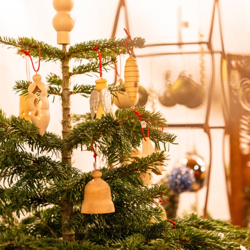 Kleiner Weihnachtsbaum mit handgeschnitztem Holzschmuck in einem warm beleuchteten Raum im Salzburger Lungau.