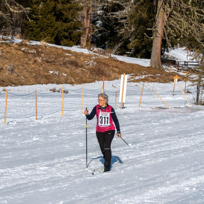 Person beim Skilanglauf im Salzburger Lungau, trägt Startnummer 911. Schneebedeckte Landschaft mit Bäumen im Hintergrund.